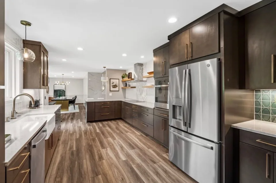 A finished kitchen with dark wood cabinets, white countertops and a stainless refrigerator - a Price Building Services project.