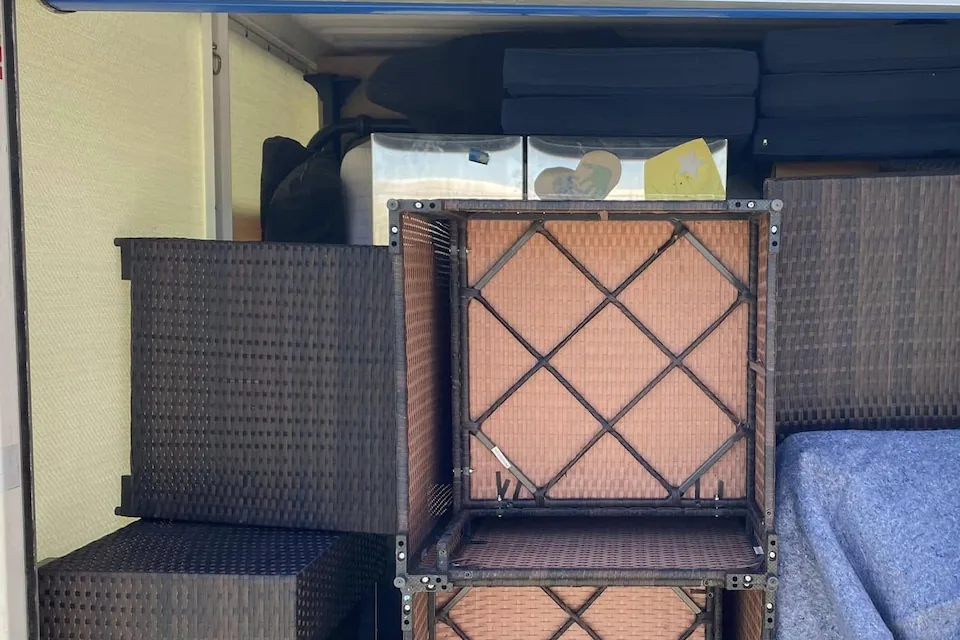 Patio furniture and cushions stacked tightly inside a portable storage container.