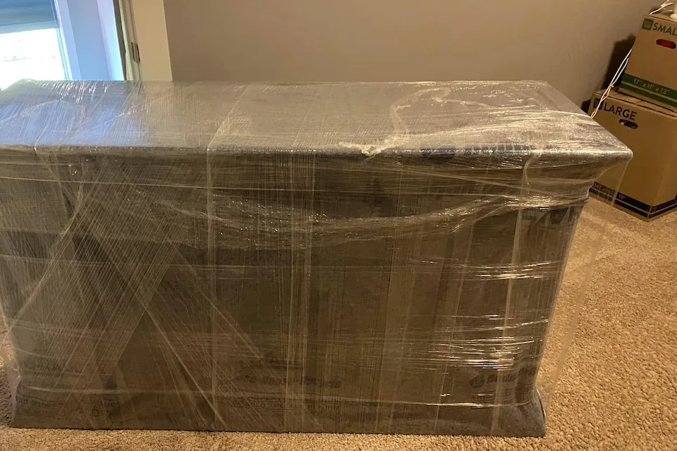 A dresser wrapped in moving pads and stretch wrap, ready to be moved.